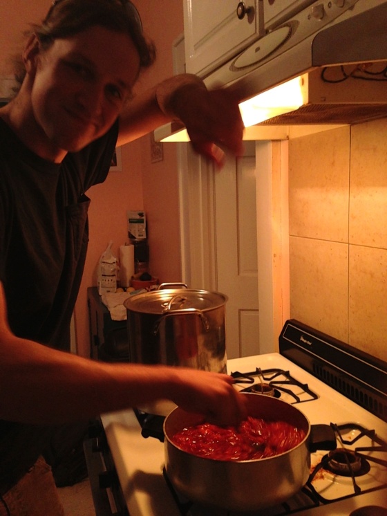 Alex tenderly stirring the smashed strawberry and sugar mixture. The big, covered pot holds the 1/2 pint jelly jars boiling for sterilization.